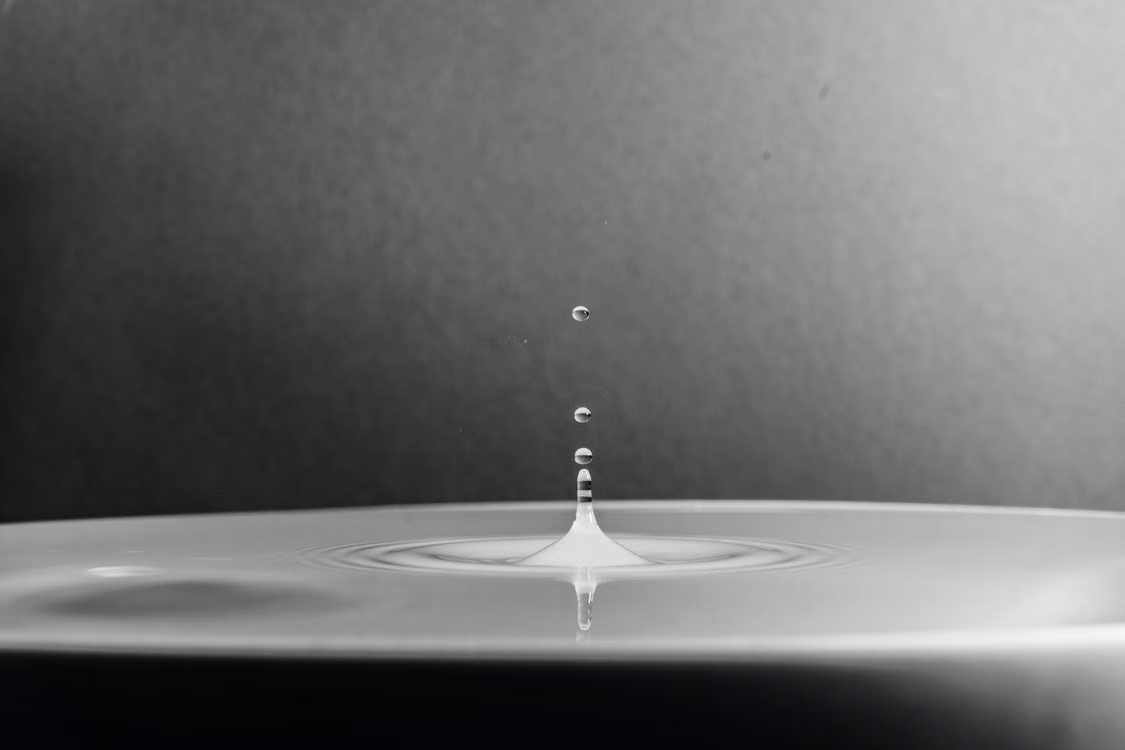 A high-definition macro shot capturing a water drop splash in black and white.