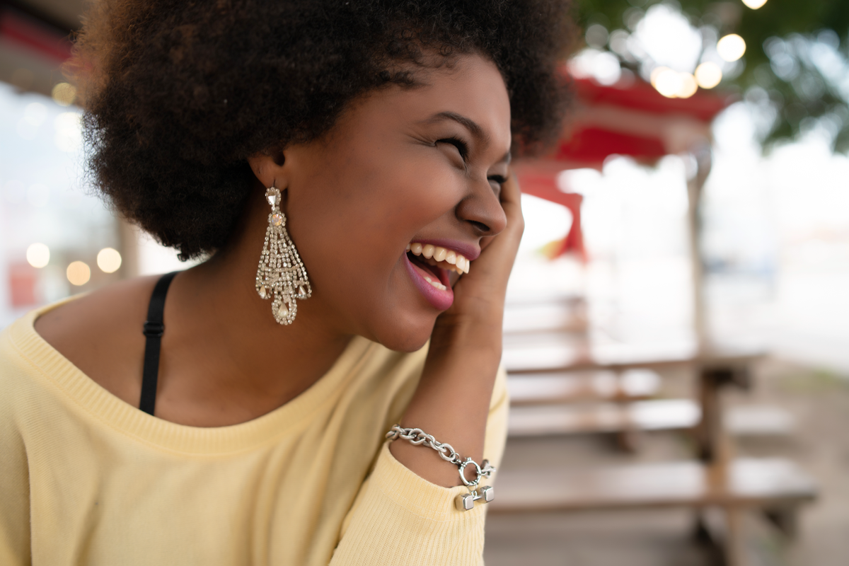 Teen jewelry by SARAH'S WHISPER - stylish young woman in chandelier earrings and charm bracelet smiling