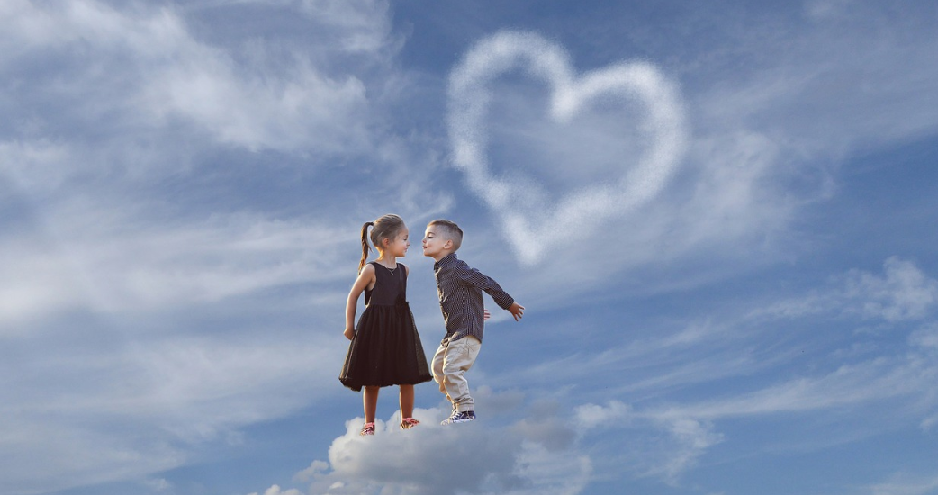 Two kids, a boy and a girl, making gestures of love for each other, flaunting children's jewelry.