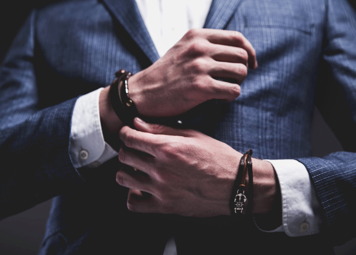 A young man in a blue suit is wearing an infinity bracelet.