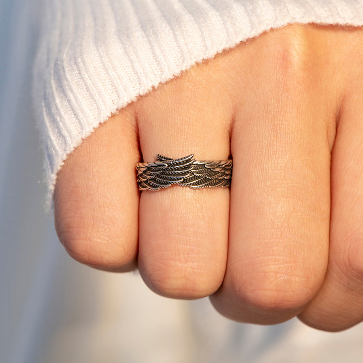 Person wearing inspirational angel wing rings hand shot